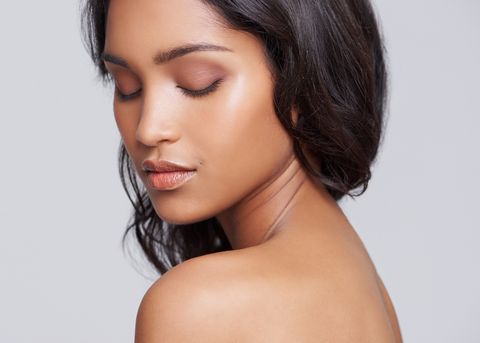 Woman with luminous, well-hydrated skin glancing over her bare shoulder