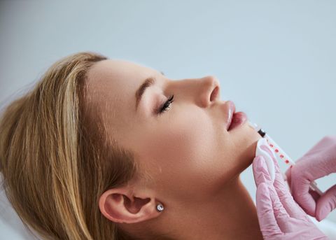 Woman receiving a neurotoxin injection along her jawline from a gloved provider